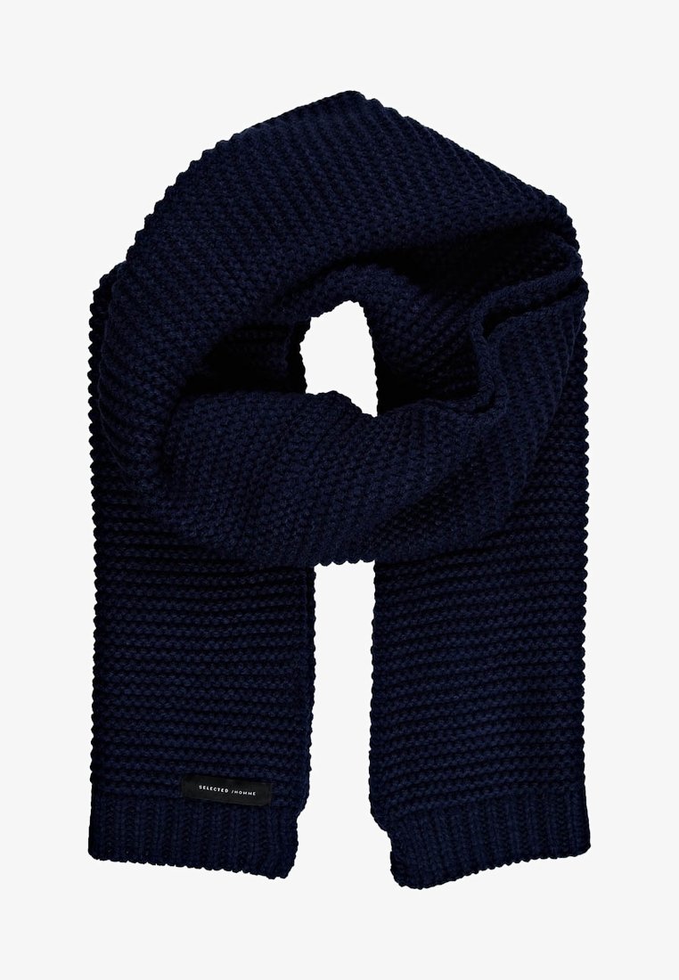 Écharpe en tricot bleu marine avec une texture côtelée épaisse, forme rectangulaire, design plié en boucle et petite étiquette noire portant l'inscription "SELECTED HOMME".