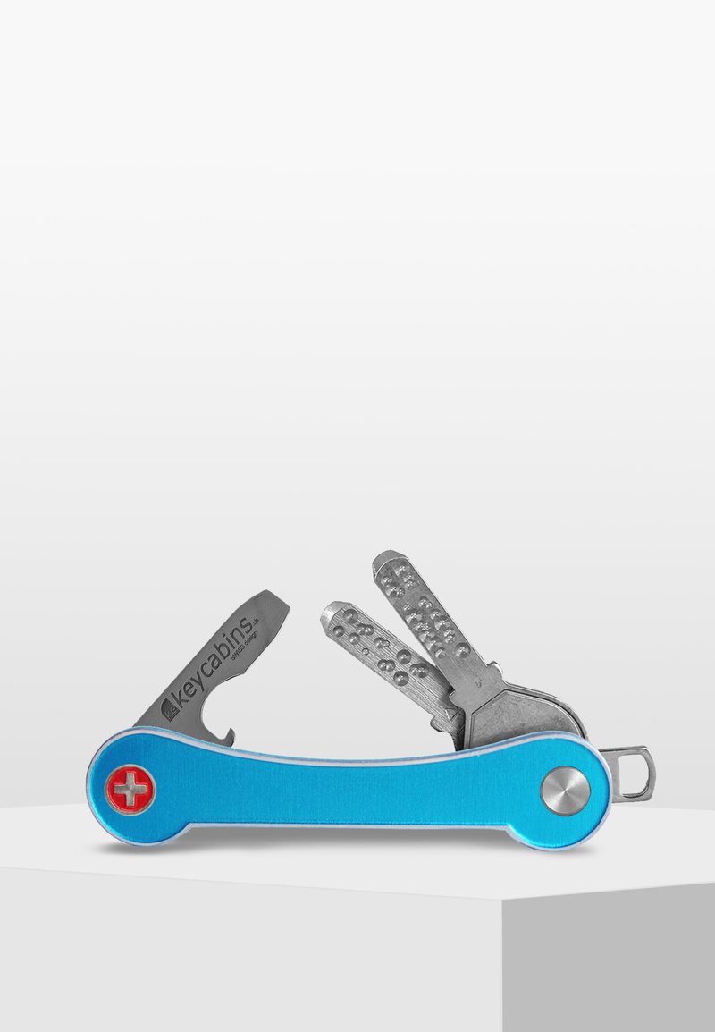 Multiverktyg med en blå aluminiumkropp. Har en silverfärgad kniv, två metallnycklar och en rund röd detalj med ett vitt kors.