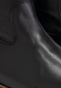 Stivale in pelle nera alla caviglia con una finitura liscia, punta arrotondata e dettagli di cucitura delicati lungo i lati.