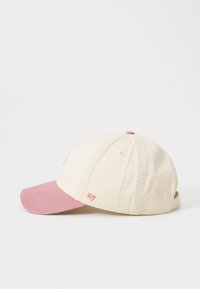 Cotton baseball cap with a beige crown and pink brim, featuring embroidered "24/7" detail. Soft texture and adjustable strap at the back.