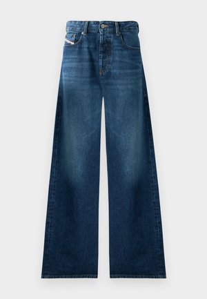 Jeans de denim de perna larga em lavagem escura. Apresenta design tradicional de cinco bolsos, fecho de botão e um leve desbotamento nas coxas.