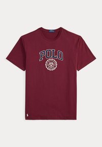Μπορντό κοντομάνικη μπλούζα με κείμενο "POLO" και σήμα Polo Ralph Lauren New York μπροστά, μικρό λευκό λογότυπο κοντά στο στρίφωμα.