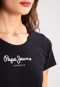 Černé bavlněné tričko s kulatým výstřihem a krátkými rukávy, s bílým textovým logem "Pepe Jeans London" na přední straně.