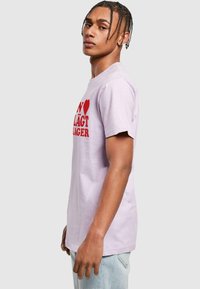 Lyse lilla bomulds t-shirt med korte ærmer, der har et fedt rødt trykt tekstdesign. Klassisk rund halsudskæring og lige skæring.