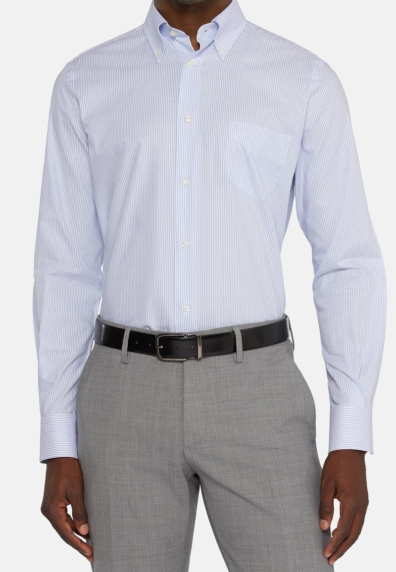 Koszula w niebiesko-białe paski na guziki z kieszenią, zestawiona z szarymi spodniami o fakturze i czarnym paskiem. Długie rękawy, kołnierzyk.