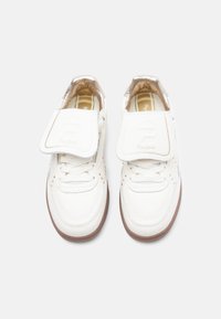 Valged nahast vabaajajalanõud elegantse disainiga, millel on silmapaistev takjapael, kuldsed detailid ja pruun kummist tald. Ees paelutatud.