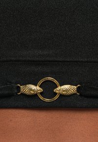 Black fabric with a smooth texture, featuring a gold snake-shaped clasp and a circular "Just Cavalli" accent in the center.