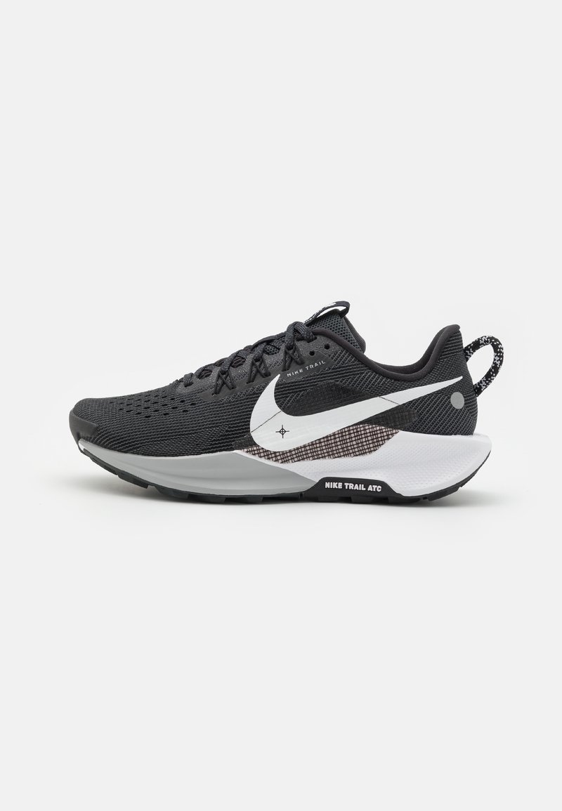 Chaussure de course Nike Trail ATC noire et blanche avec tige en mesh, grand logo swoosh blanc, fermeture à lacets et semelle texturée pour la course sur sentier.