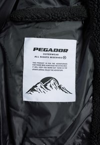 Abbigliamento esterno nero con un interno dalla texture morbida, dotato di un'etichetta bianca con la scritta "PEGADOR" e una grafica di montagna nera.