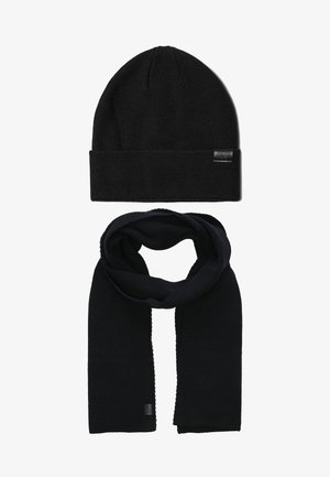 Zwarte beanie met een omgeslagen rand en een gestructureerd breipatroon, gecombineerd met een bijpassende zwarte sjaal met een glad, geweven ontwerp.
