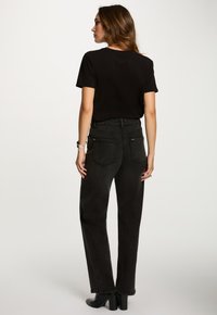 Sort t-shirt og sort denimjeans i høj talje med lige ben, baglommer og ankelstøvler med blokhæl.