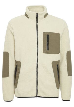 Fleece bunda v krémové barvě s olivově zelenými nylonovými nášivkami. Má vysoký límec, přední zip a kapsy na zip na hrudi a po stranách.