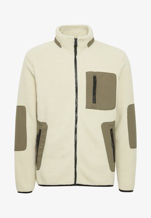 Fleecejakke i creme med olivengrønne nylonlapper. Har en høj krave, frontlynlås og lynlåslommer på brystet og siderne.