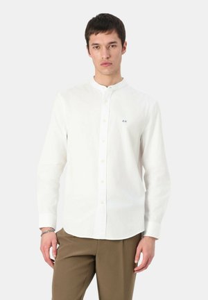 Camicia bianca a maniche lunghe con colletto button-down, caratterizzata da un piccolo logo blu sul lato sinistro del petto e un design dal taglio rilassato.