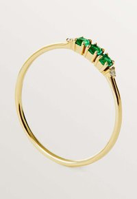 Anillo de oro con tres piedras preciosas verdes y un pequeño acento de diamante, con una banda pulida y suave y un diseño minimalista.