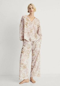 Ensemble de vêtements de détente à motif floral dans des teintes de rose doux et de beige, comprenant un haut boutonné à manches longues et un pantalon ample avec cordon de serrage.