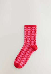 Rote und pinke kniehohe Socken mit einem Rautenmuster, einem einfarbigen roten Bündchen und Zehen, aus einem dehnbaren Stoff gefertigt.