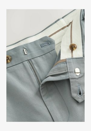 Šviesiai pilkos kelnes su užtrauktuku, rudos sagties ir baltu vidiniu pamušalu. Yra siuvinėti detalės ir metalinis kabliukas.