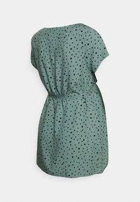 Zelené šaty z látky s krátkými rukávy, zdobené černými puntíky a stahovacími pásky v pase, s hladkou strukturou a volným střihem.