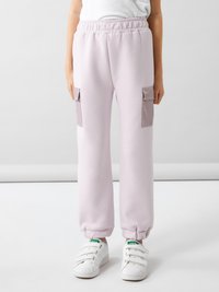 Pantaloni de trening roz deschis cu talie elastică, manșete cu aspect în dungi și două buzunare laterale dintr-un material contrastant. Asortați cu adidași albi.