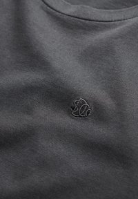 Mørkegrå bomulds-T-shirt med rund halsudskæring og broderet logo i en let mørkere nuance, med en glat, jævn tekstur.