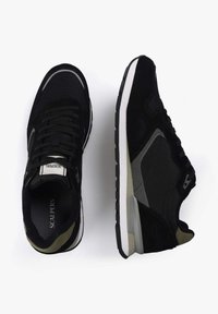 Zapatillas deportivas negras con una parte superior de malla y ante, que presentan un acento gris, una entresuela blanca y una suela externa de goma negra texturizada.