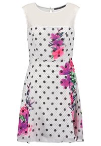 Robe blanche avec des pois noirs et un imprimé floral dans des tons de rose et de vert, avec un haut en transparence et une taille cintrée.