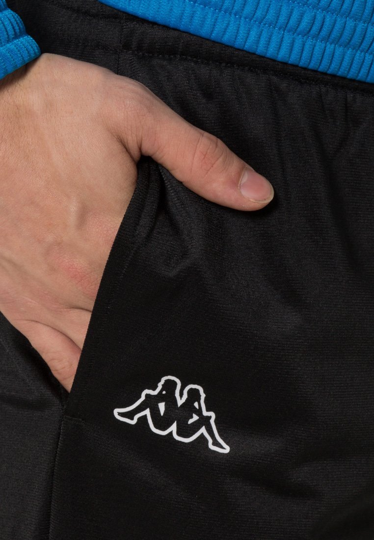 Pantaloni sportivi neri con una texture liscia, dotati di una vita blu. Un piccolo logo Kappa bianco è visibile sulla tasca laterale.