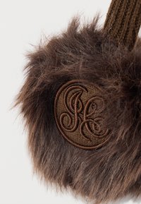 Smeđi privjesak od umjetnog krzna s okruglim smeđim tkanim zakrpom na kojoj su ukrašeni inicijali izvezeni svijetlosmeđom niti.