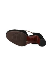 Scarpa con tacco in suede nera dal design curvo, caratterizzata da una suola marrone liscia e una fascia che attraversa il piede. Motivo testurizzato nella parte anteriore.