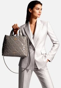 Borsa a mano grigia in vernice con design trapuntato, dettagli in metallo dorato, manici superiori e tracolla rimovibile. Logo visibile sulla parte anteriore.