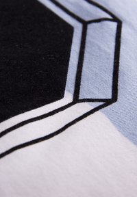Textil de algodón con un diseño geométrico que presenta colores negro, azul claro y blanco. La superficie tiene una textura suave con un fino cosido.