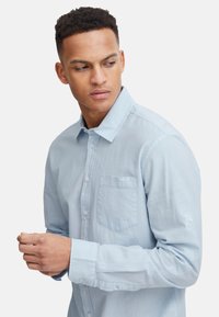 Helles blaues Hemd mit langen Ärmeln, einer Brusttasche und einer weichen, strukturierten Oberfläche. Verfügt über geknöpfte Manschetten und einen Kragen.