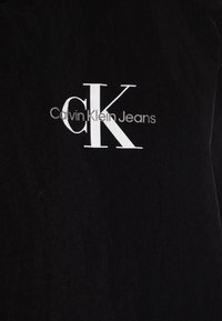Sort bomuld t-shirt med en hvid "CK" logo og teksten "Calvin Klein Jeans" i en enkel, moderne skrifttype. Blød tekstur, afslappet pasform.