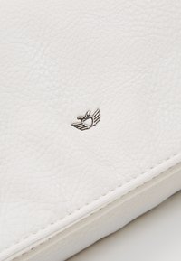 Pochette in pelle bianca con superficie testurizzata, dettaglio del logo metallico a forma di cuore e ali, e linee di design pulite e semplici.