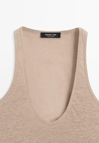 Beige sleeveless knit top with deep round neckline and Massimo Dutti brand label at the back of the neck.