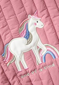 Tissu matelassé rose avec un unicorn brodé en blanc ayant une crinière multicolore, accompagné d'un arc-en-ciel et du texte "unique en son genre".