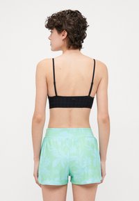 Black crochet bralette paired with mint green shorts featuring a floral pattern. The shorts have a smooth texture and elastic waistband.