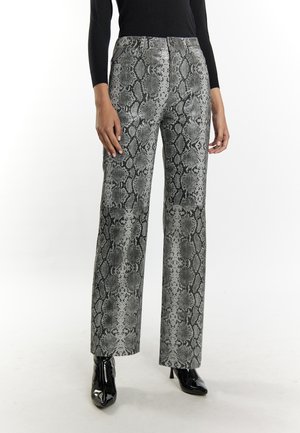 Person wearing high-waisted, wide-leg pants with black and gray snake print, black long-sleeve top, and black pointed-toe ankle boots.