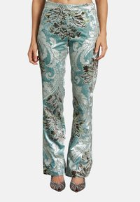 Turquoise patroonbroek van een fluweelachtig materiaal met ingewikkelde bloemenontwerpen in donkergroen en zilver. Heeft een recht model.