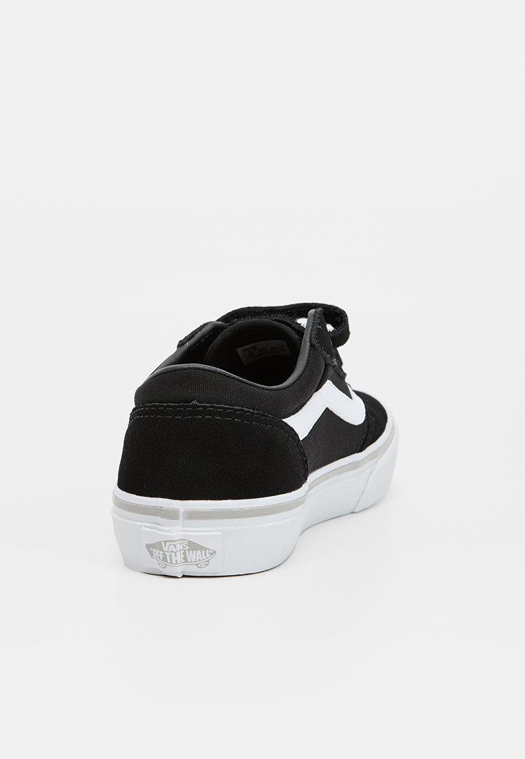 Zapatilla deportiva de ante negro con un diseño de zigzag blanco en el lateral. Cuenta con una suela de goma blanca y un cuello acolchado para mayor comodidad.