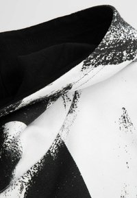 Czarny i biały t-shirt graficzny z abstrakcyjnym wzorem; gładka tekstura i krój z okrągłym dekoltem, ukazujący wyrazisty kontrast kolorów.