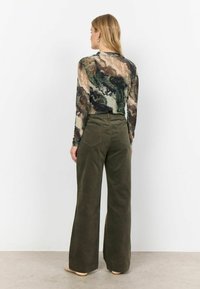 Maglia a maniche lunghe con un motivo astratto multicolore, abbinata a pantaloni in corda verde oliva a vita alta e a gamba larga.