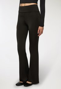 Pantaloni neri a palazzo con vita alta e ampia, realizzati in un tessuto morbido ed elasticizzato. Il design si restringe delicatamente dalla ginocchio in giù.