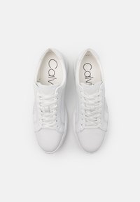 Zapatillas blancas con parte superior de cuero liso, puntera redonda y cordones planos. Incluye una plantilla acolchada y detalles de costura mínimos.