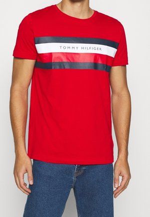 Czerwona bawełniana koszulka z okrągłym dekoltem, krótkimi rękawami oraz nadrukiem z czarno-białymi poziomymi paskami i napisem "TOMMY HILFIGER" z przodu.