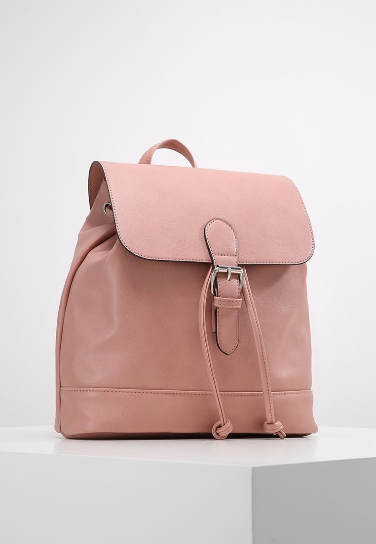 Zaino in pelle rosa pallido con chiusura a patta, cordoncino regolabile, hardware in argento e superficie liscia. Forma rettangolare semplice.