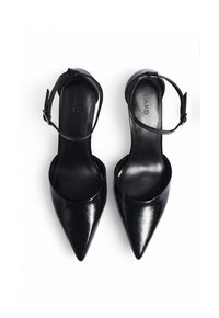 Mustad varbaga kõrged kontsad mustad kingad, millel on pahkluuringid, paigutatud kõrvuti valgel taustal.