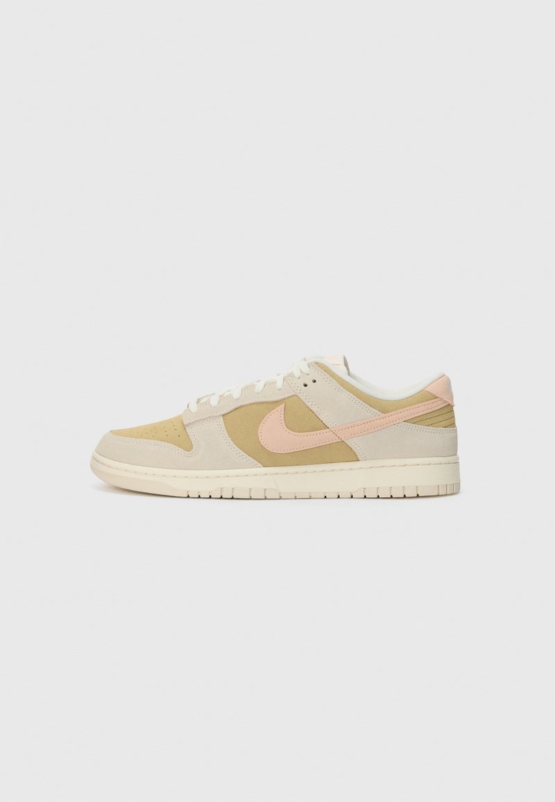 Baskets basses avec des panneaux beige, marron clair et rose clair, des lacets blancs et une semelle en caoutchouc sur un fond uni gris clair.