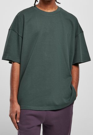 Mørkegrøn oversized t-shirt lavet af blødt bomuld, med rund hals og korte ærmer, en glat tekstur og minimale syningsdetaljer.